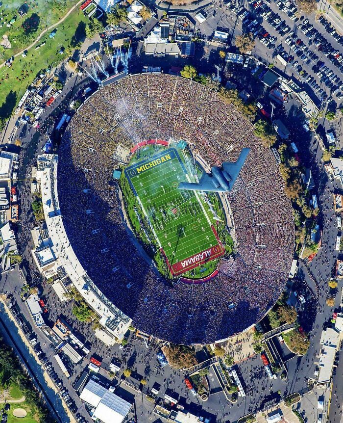 Aerial view of a packed football stadium with Michigan and Alabama team logos during USA event
