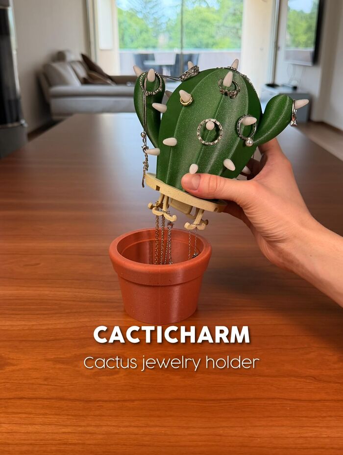 3D printed cactus jewelry holder with rings in a terracotta pot on wooden table