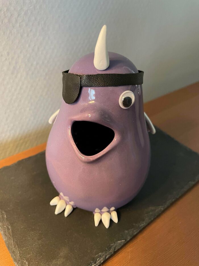 A cute purple ceramic creature with an eyepatch, representing whimsical thrift store finds.