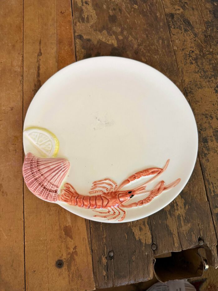 A white ceramic plate with a raised lobster design, one of the unique thrift store finds.