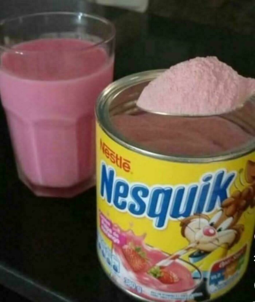 A glass of strawberry milk next to a Nesquik tin, evoking nostalgic pics of childhood in the early 2000s
