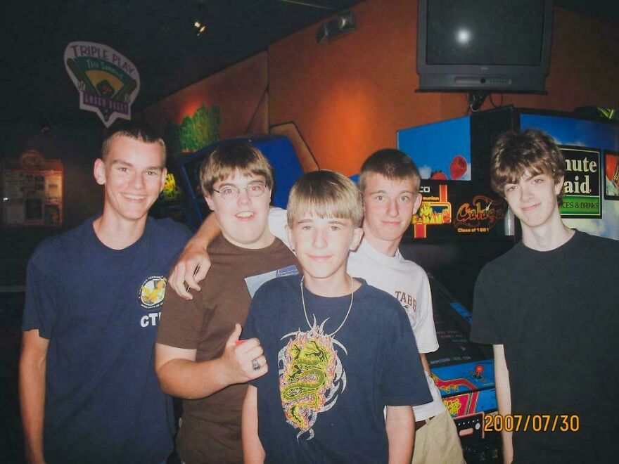 Five teenage boys hanging out together in an arcade from the early 2000s.