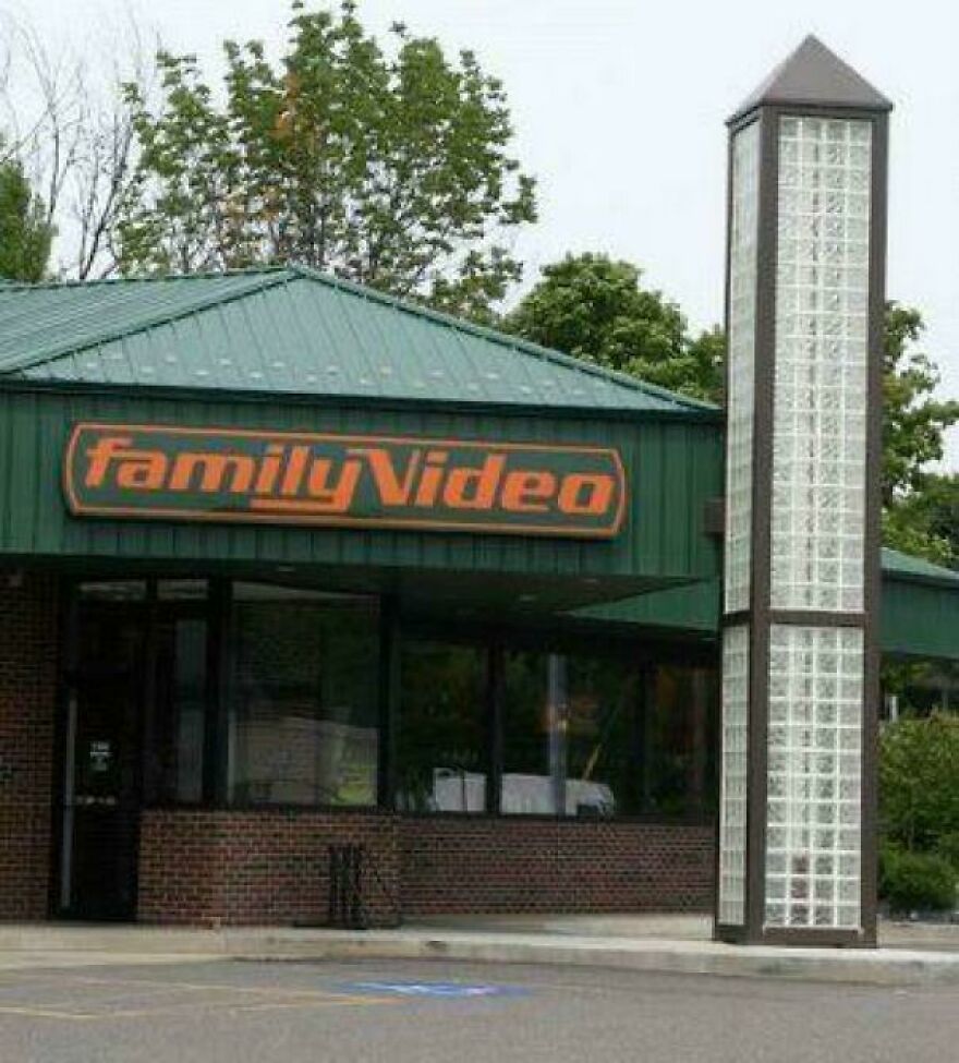 An exterior shot of a classic Family Video rental store with its green roof and sign, reflecting early 2000s life