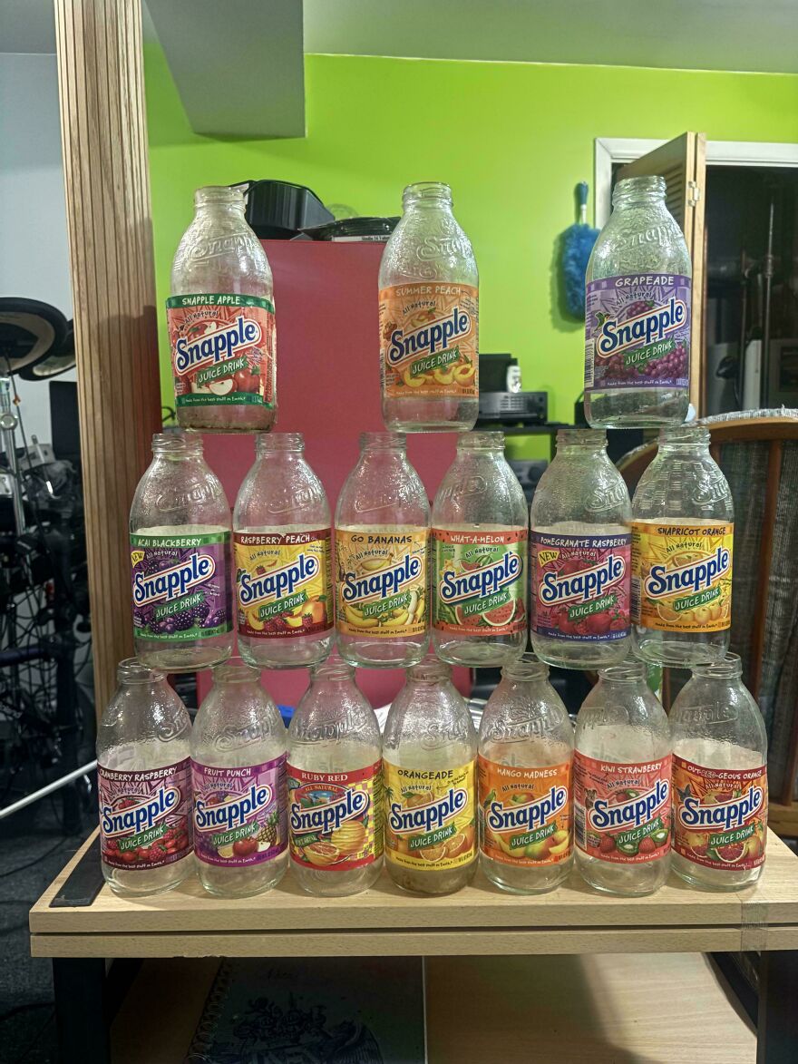 A pyramid of vintage glass Snapple bottles showcasing various flavors from the early 2000s.