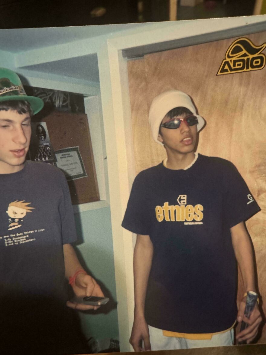 Two teenagers in the early 2000s wearing skater clothing like Etnies and an Adio sticker on the door.
