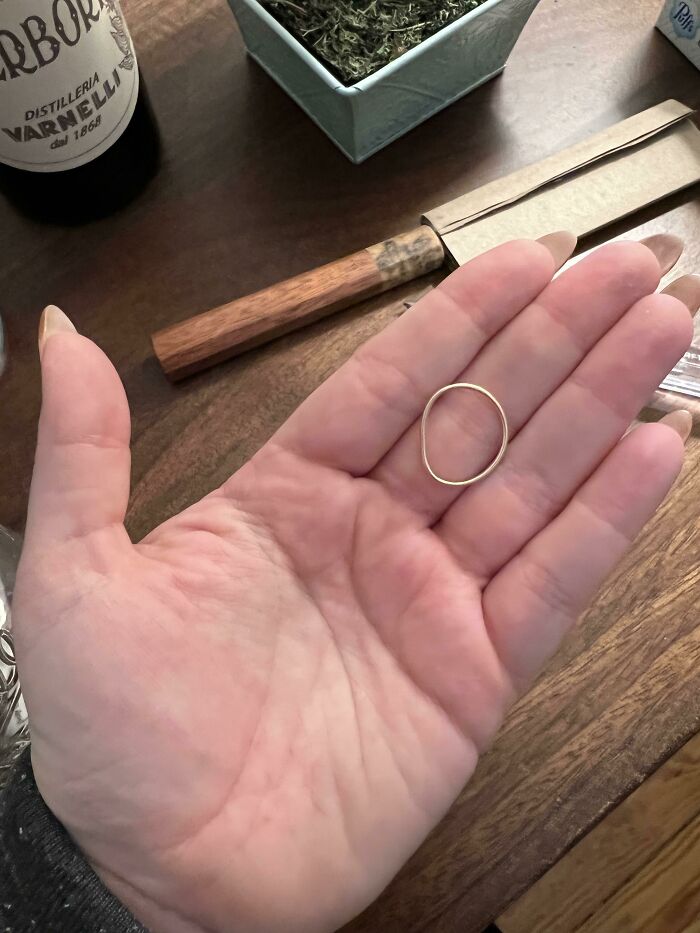 Cool photos of a tiny golden ring resting on a person’s open palm