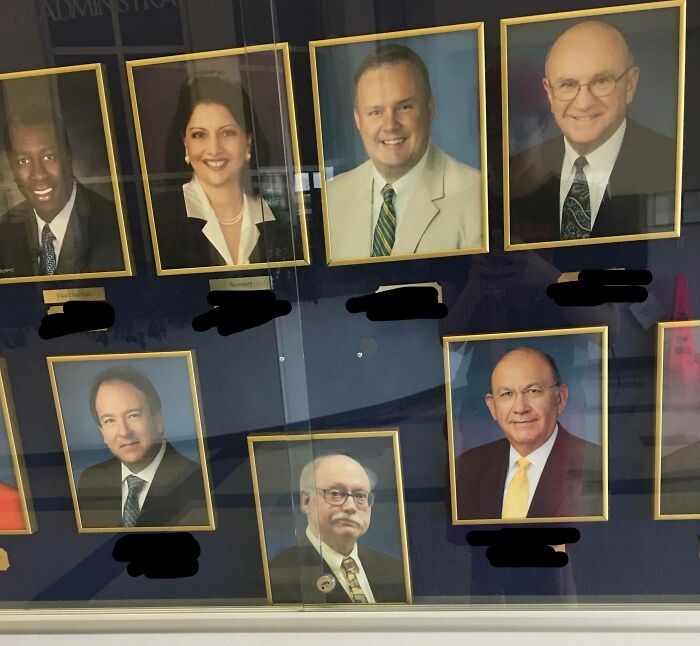 Interesting photo of a slightly tilted portrait frame among straight headshots on a wall