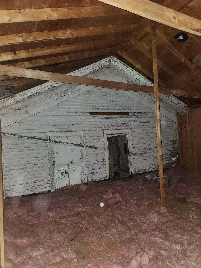 A cool photo showing a preserved old house facade hidden inside a modern attic space.