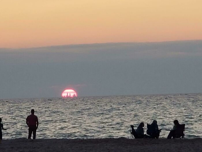 An interesting photo of a sunset over the sea with a distant ship silhouette inside the sun.