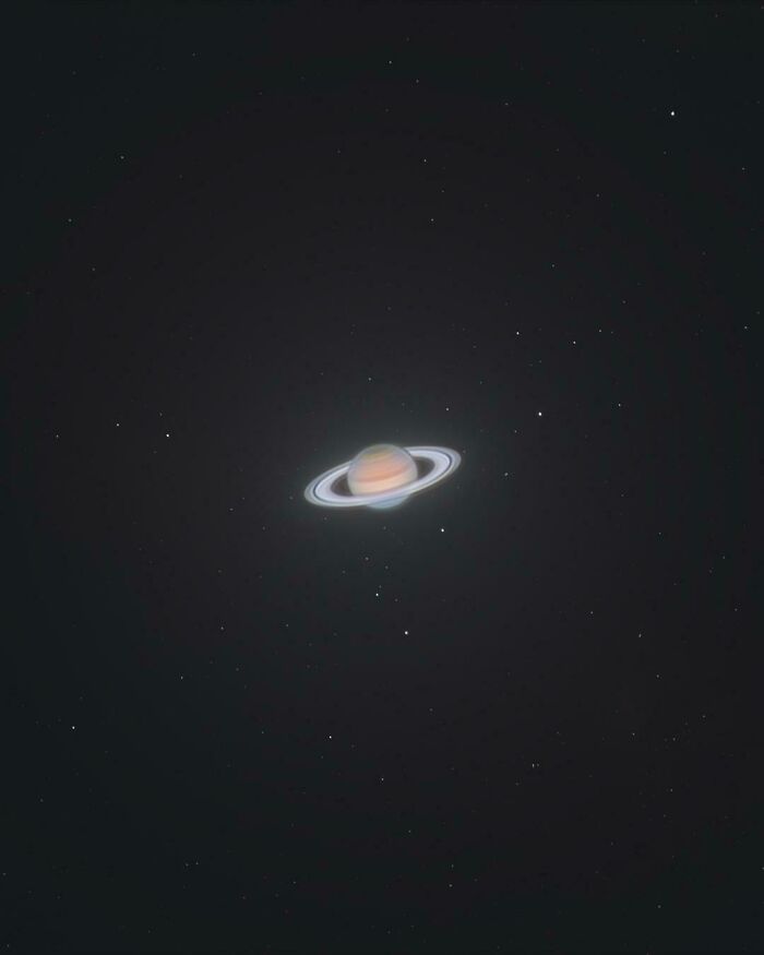 A cool photo of the planet Saturn and its visible rings glowing in the dark night sky.
