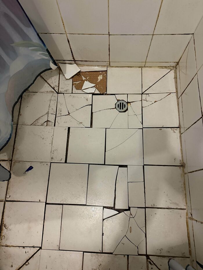 Severely cracked tiles on a bathroom floor showing a bad renting and booking experience