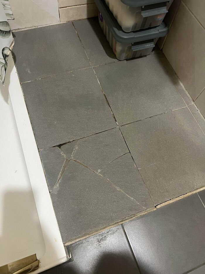 Cracked and broken floor tiles in a bathroom, showing a disappointing renting and booking experience.