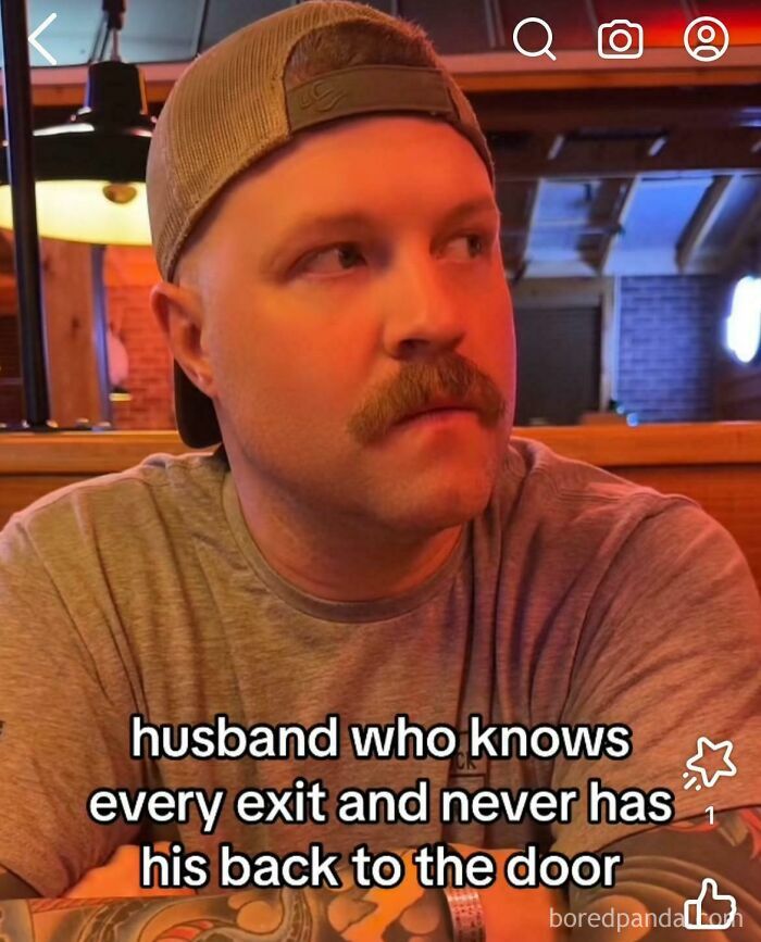 Man with tattooed arms and mustache sitting in restaurant looking sideways showcasing tough guy look