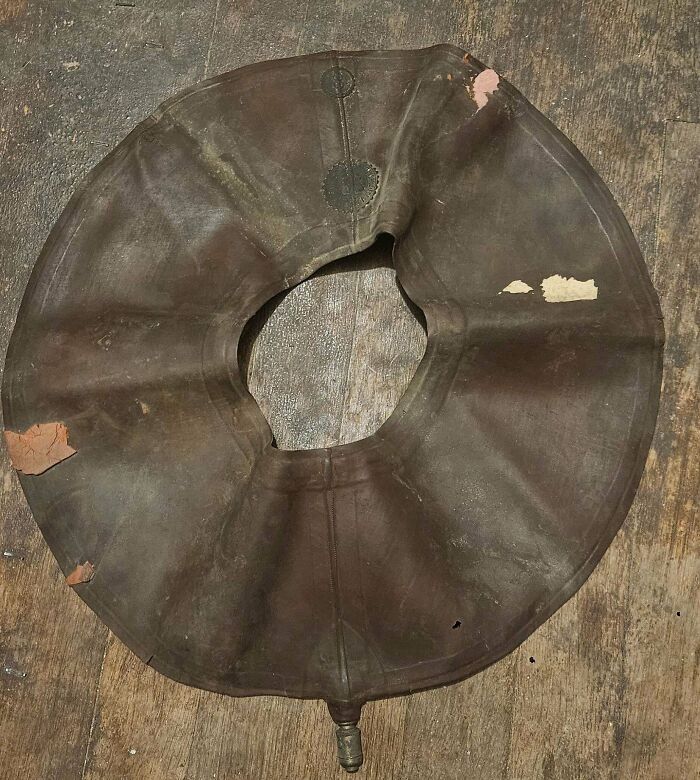 Round vintage leather flotation device lying on a wooden floor, a rare find for antique lovers.