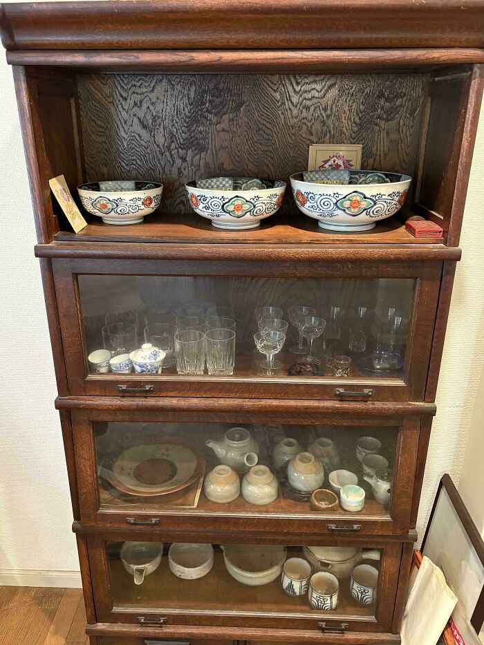 Wooden stackable bookcase filled with ceramic bowls and glassware, a treasure piece for antique lovers.