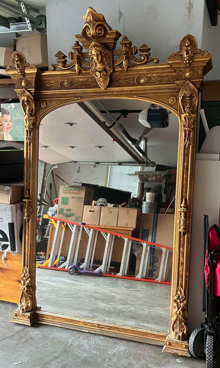 Large ornate gold antique mirror with elaborate carved top arch display, a unique treasure for antique lovers.