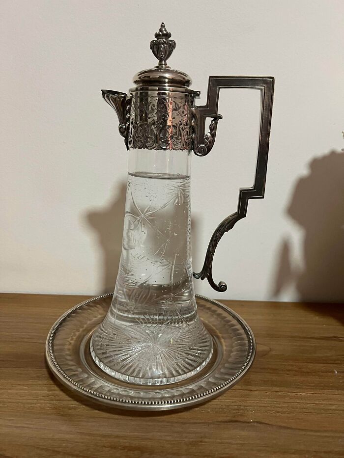 Antique lovers treasure vintage silver and crystal claret pitcher with intricate metallic lid and decorative handle.