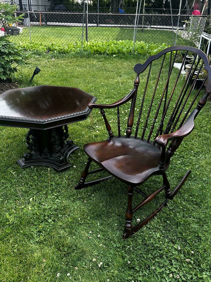 A classic dark wood rocking chair and matching side table placed on a lawn, representing old treasures.