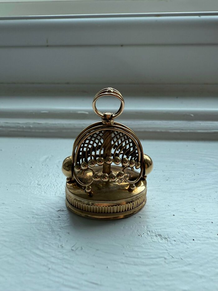 Intricate gold wax seal stamp on a white surface, one of many old treasures for antique lovers.
