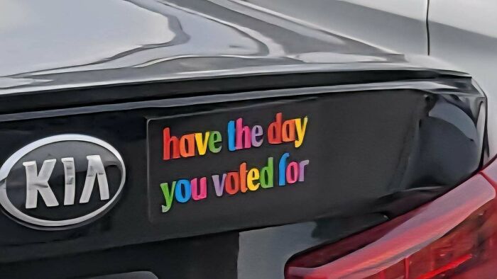 A colorful bumper sticker on a Kia reading have the day you voted for.