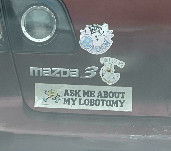 Back of a car with a decal reading Ask me about my lobotomy, among wild bumper stickers.