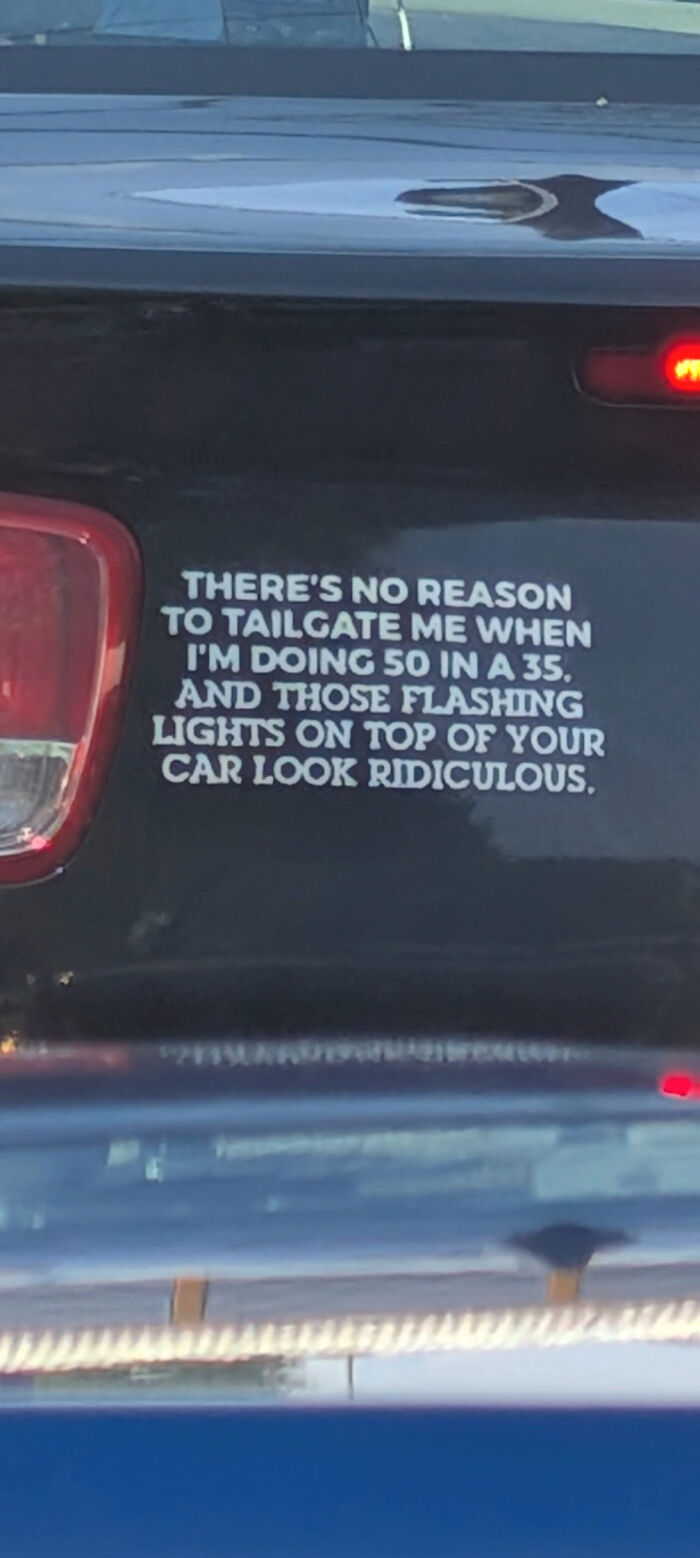 A funny decal on a car rear window about speeding and police car lights.