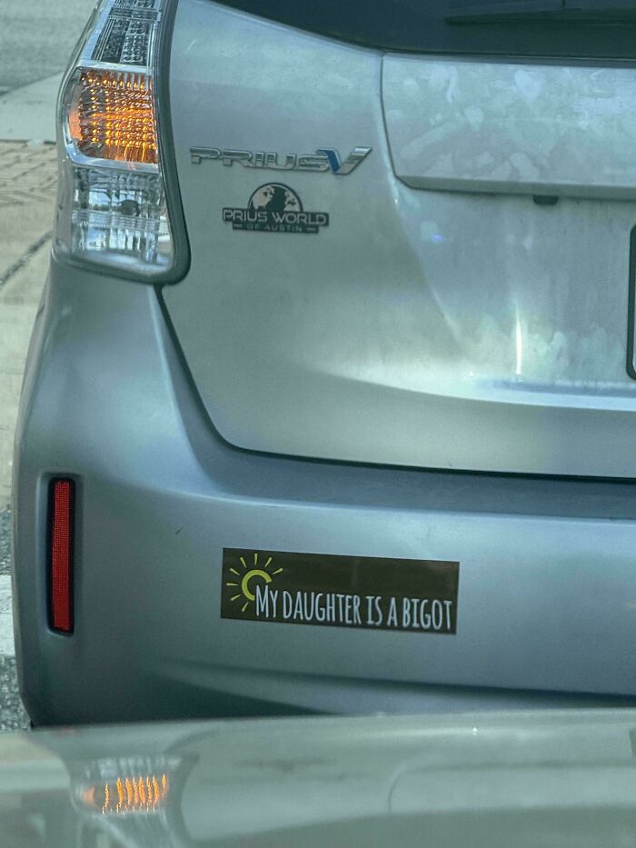 A funny bumper sticker on a silver Prius reading MY DAUGHTER IS A BIGOT.