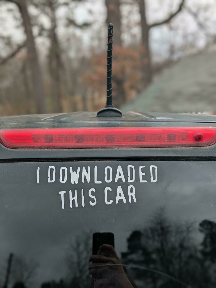 Decal bumper stickers on a car rear windshield saying I downloaded this car.