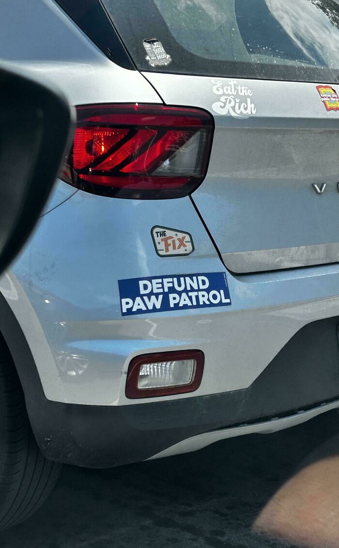 Wild bumper stickers reading Defund Paw Patrol on a silver car.