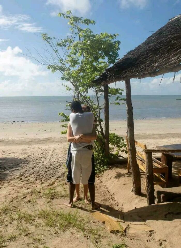Beach scene where a couple's embrace is hidden by a tree, creating a visual illusion