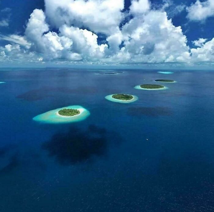 Aerial view of islands with clear water and clouds reflecting on the ocean