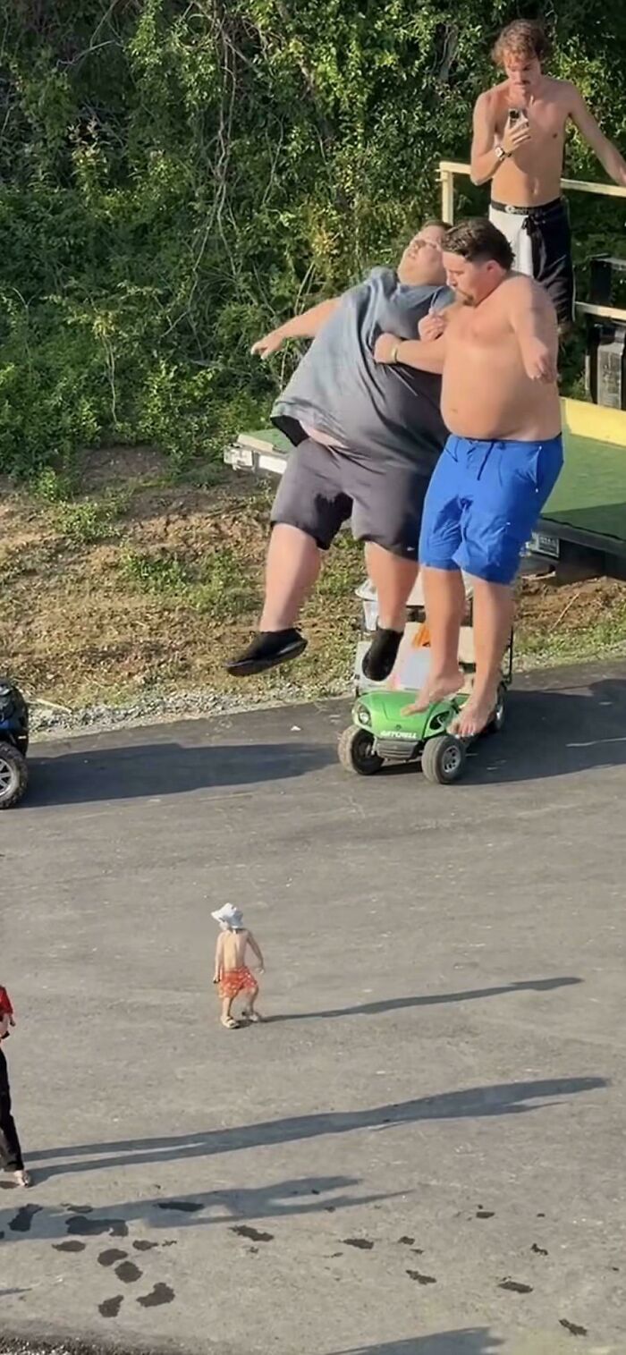 Two people appear to be floating above a small toy vehicle in a funny photo illusion
