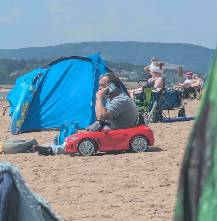 Man appears inside a toy car at beach, an optical illusion confusing the eye