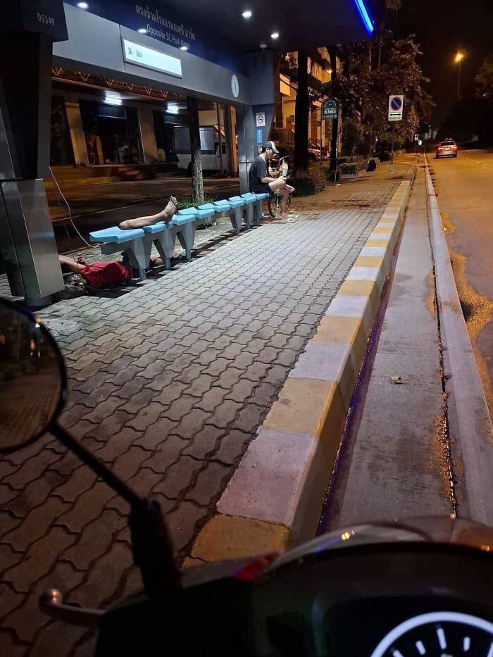 Bus stop scene with person’s legs appearing separate under bench