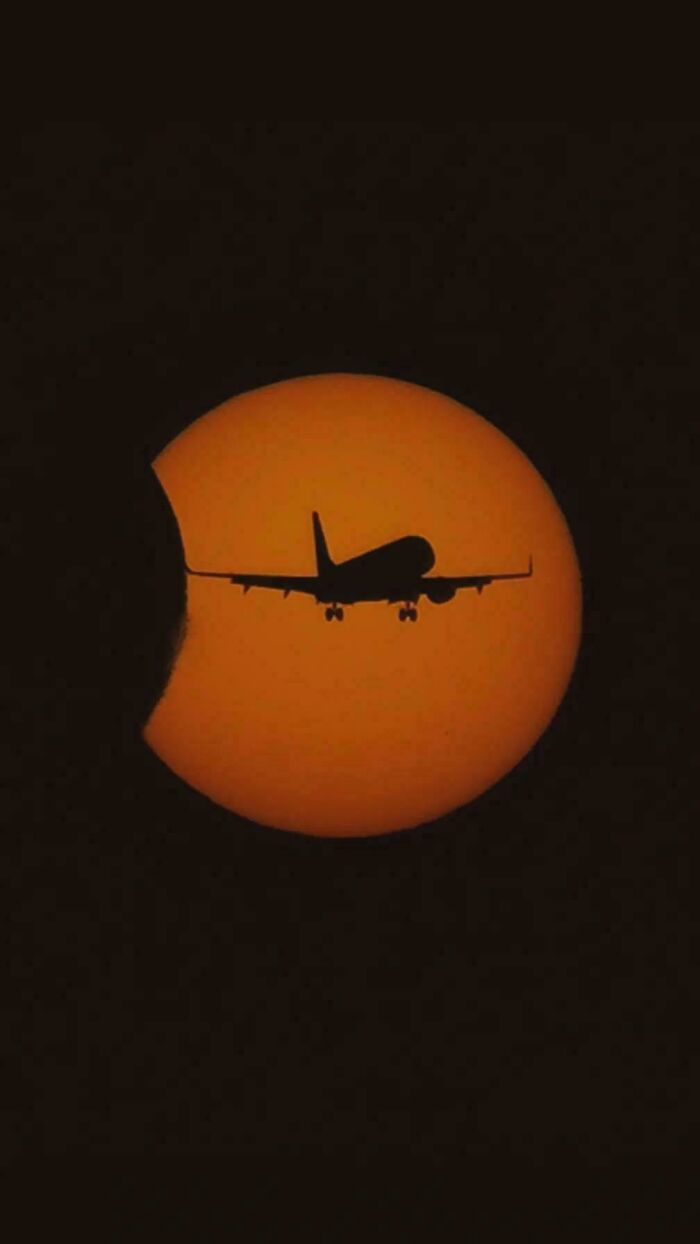 Airplane silhouette crossing partial solar eclipse creating eye confusion