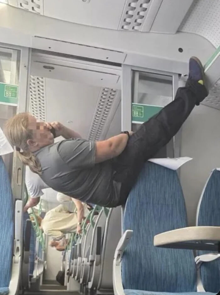 Person appearing to hang sideways on train seats creating visual confusion