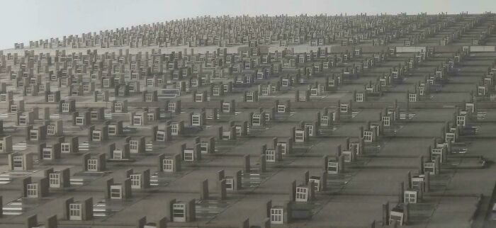 Facade of a tall building with hundreds of identical air conditioning units in a grid