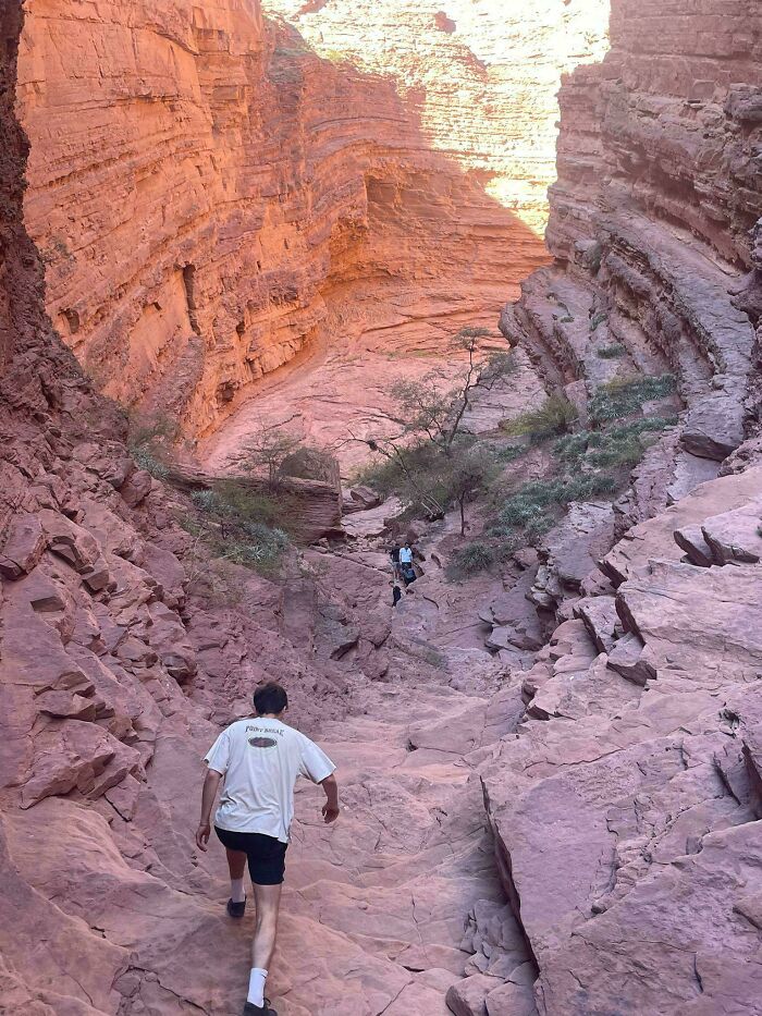 Hiking trail through red rock canyon with people descending steep rocky path