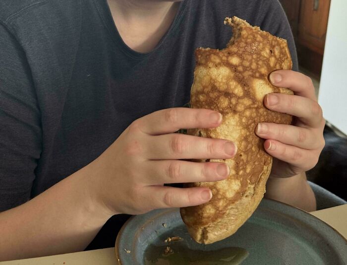A person holding a massive pancake like a taco, representing cute things wives do