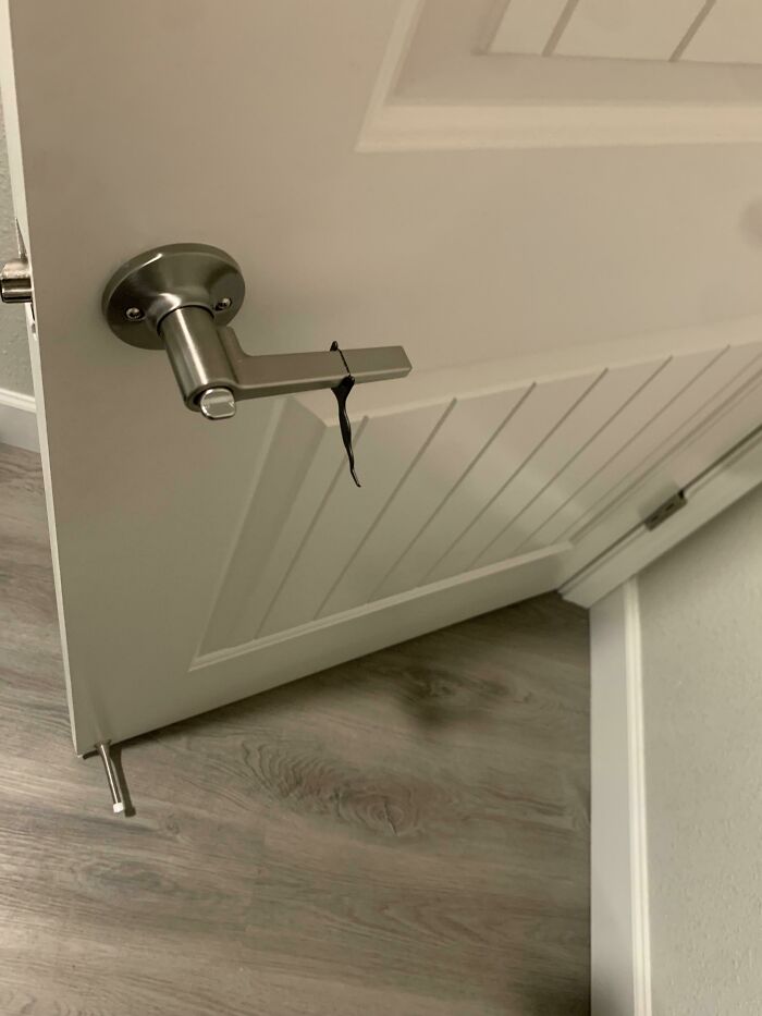 A simple black hair tie wrapped around a silver metal door handle