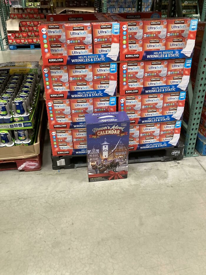 Stack of laundry products in a store with an out-of-place Christmas beer advent calendar, showcasing cute things wives do.