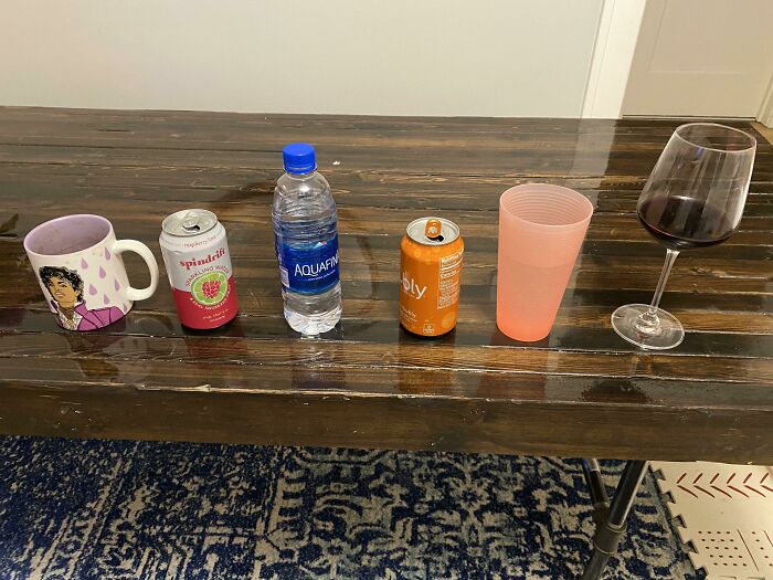 A line of different drinking cups and cans lined up on a table, highlighting unhinged things wives do.
