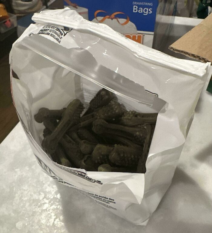A plastic bag of dog treats clumsily torn open, showing funny things wives do.