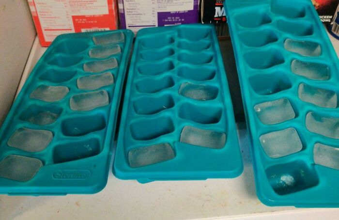 Three blue ice trays with only a few frozen ice cubes left, illustrating things wives do.