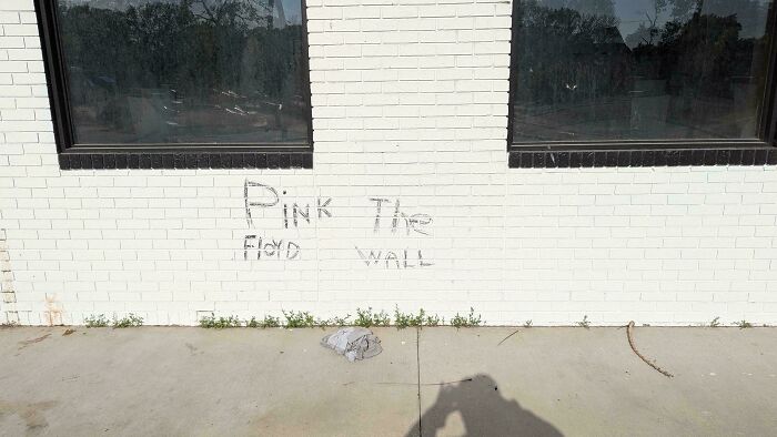 Graffiti on a white brick wall reading Pink The Floyd Wall, an example of a badly designed sign.