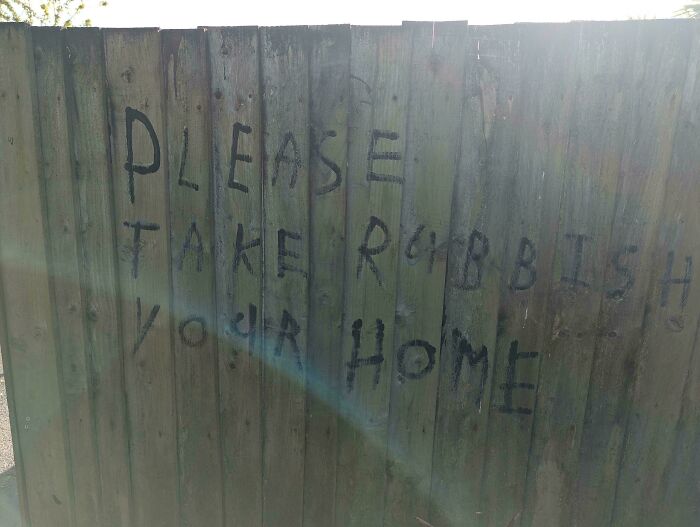 Graffiti on a wooden fence with misplaced words creating a badly designed sign.