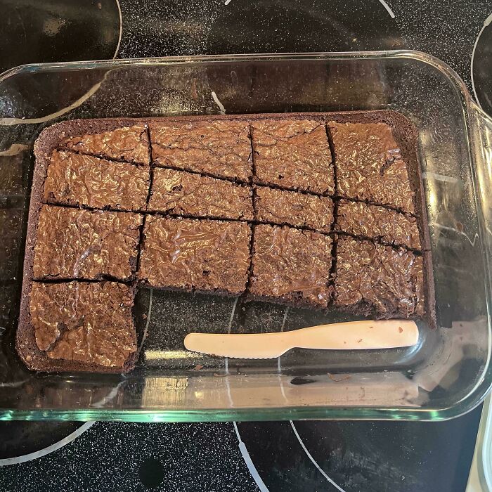 A tray of baked chocolate brownies with one slice missing, highlighting funny things wives do