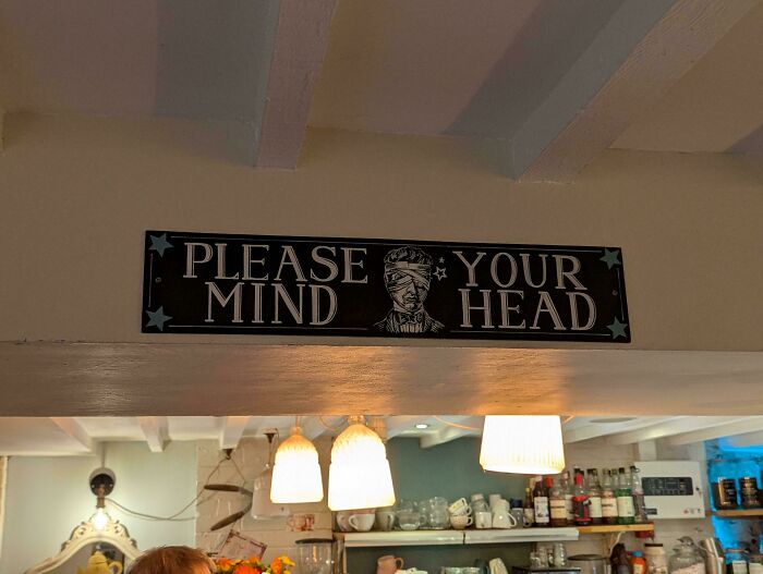 A badly designed sign that reads PLEASE YOUR MIND HEAD with a blindfolded face graphic