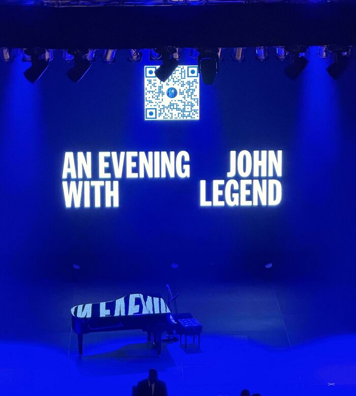 Concert stage screen displaying poorly arranged text in a funny, hilarious badly designed sign layout.