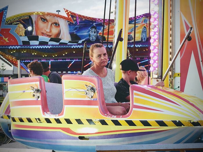 Unhappy woman sitting on an amusement park ride, capturing what unhinged things wives do.
